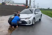 影/有你真好！伸港淹水「轎車陷水田」　工廠老闆率移工抬車