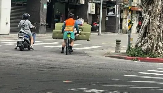 超狂！北市男騎單車「扛3人座沙發」　路人目擊看傻
