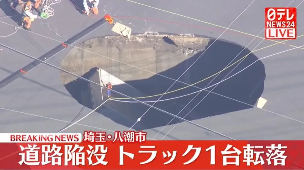 埼玉一處十字路口中央28日早上突然塌出天坑,有砂石車受困其中。(圖/翻攝NNN)