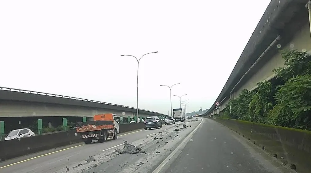 散落的砂土綿延長達200公尺，高公局緊急派員封閉車道進行地毯式清掃。（圖／翻攝畫面）