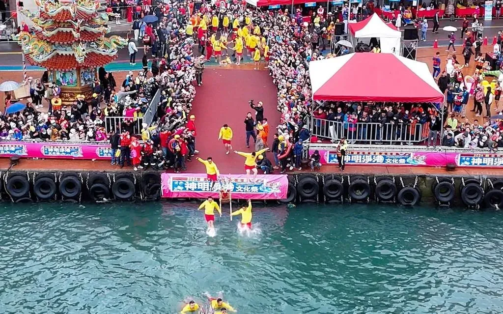 神明淨港淨海巡洋儀式,漁船繞行野柳漁港祈求平安豐收；隨後，在地青年肩負神轎衝入野柳港淨港，再赤腳穿越燃燒的火堆，完成過火儀式, 消災解厄、迎接好運。(圖／新北市政府民政局提供)