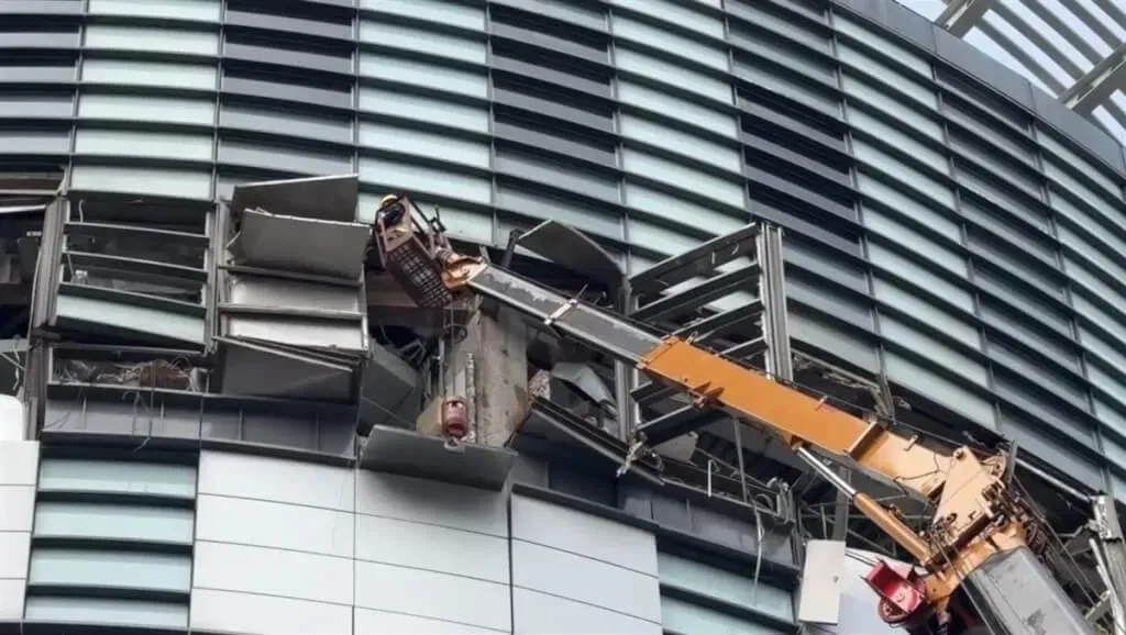 台中新光三越18日出動吊車進行外牆懸掛物拆除作業。（圖/中央社）