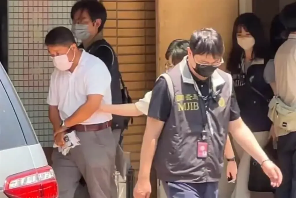 國民黨台中市黨部2日上午遭檢調搜索，調查局人員帶走台中市黨部一組總幹事伍康龍（白衣者）。（圖／中央社）