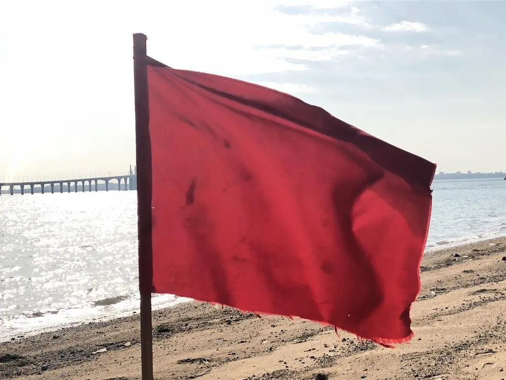 有民眾今日在金門大橋烈嶼端海灘驚見一面迎風飄揚的紅旗疑為大陸五星旗,岸巡隊獲報後隨即派員前往查證,最後確認為國軍因近期演練需要而於岸際所設的「紅色警示旗」。(圖/海巡署提供)