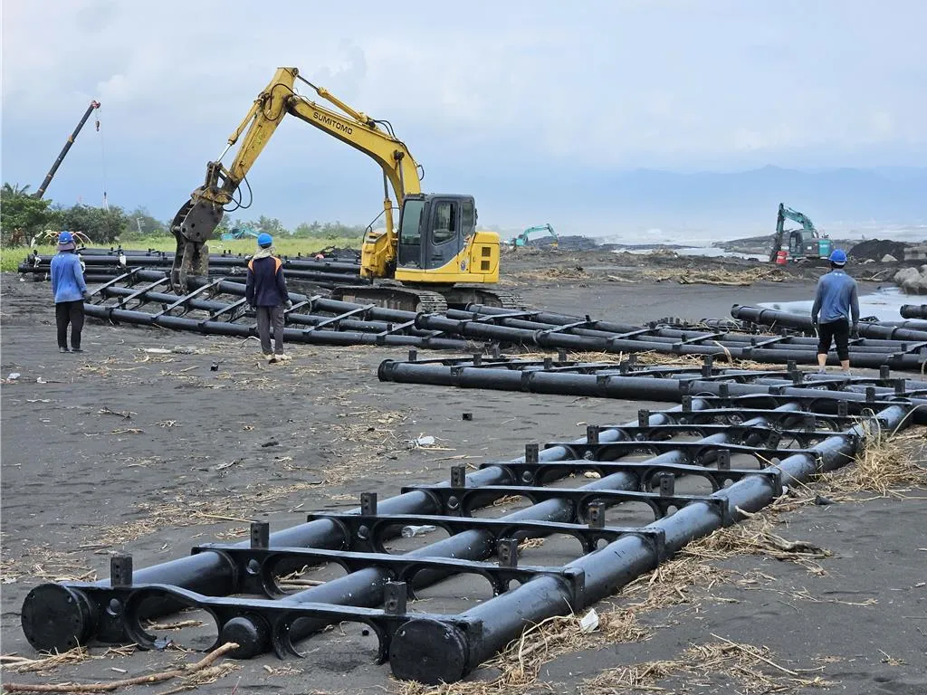 旭東公司出動重型機具清除塭豐沙灘上的海上光電測試站浮台。(報系資料照)
