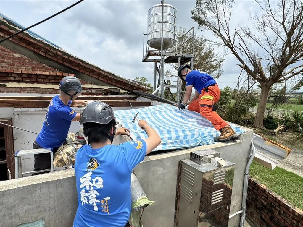 圖為台南市義消兄弟進入災區協助受災戶,在屋頂加蓋帆布。(圖/台南市消防局提供)