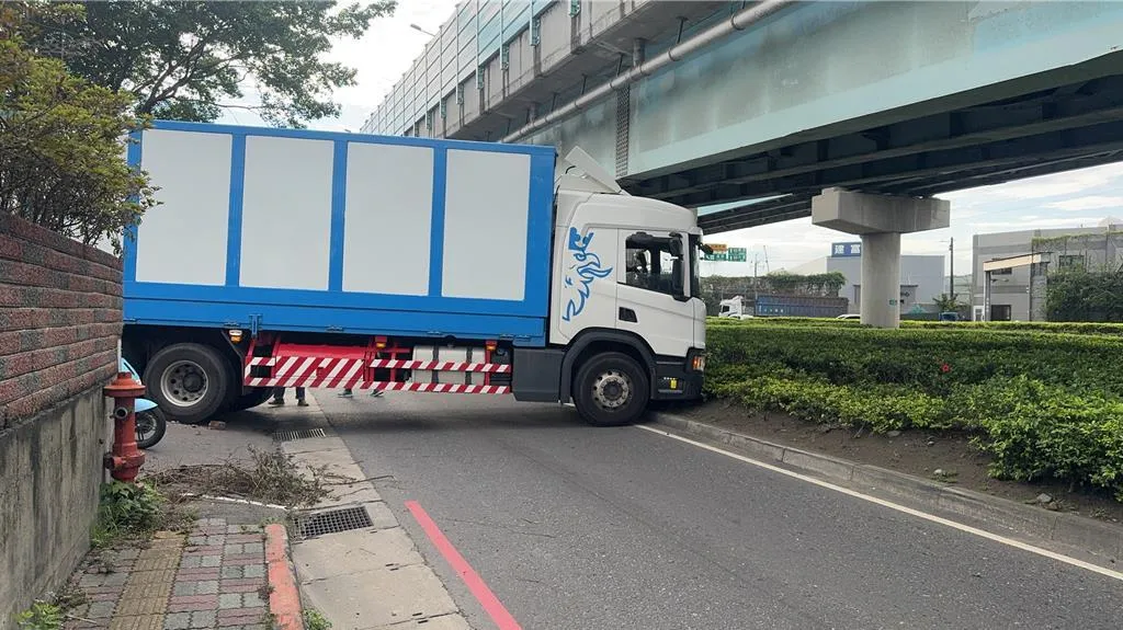 新北市五股區一輛26噸的大貨車因路面高低落差橫卡在車道。（圖／警方提供）