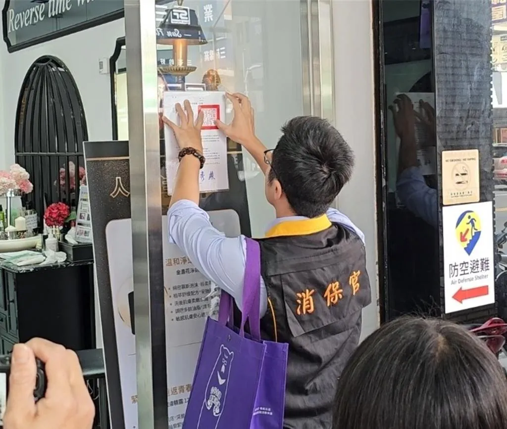 台中市法制局人員在豐原區中正路上1家美容保養品店門口張貼消費警訊，未來1個月內如未改善將繼續張貼。（圖／台中市政府提供）