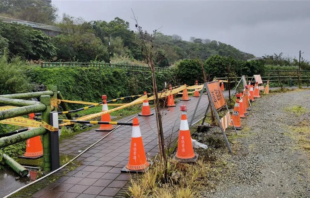 新北市三芝區八連溪步道部分護欄崩塌,水利局派員拉設警示帶管制。(圖/新北市水利局提供)