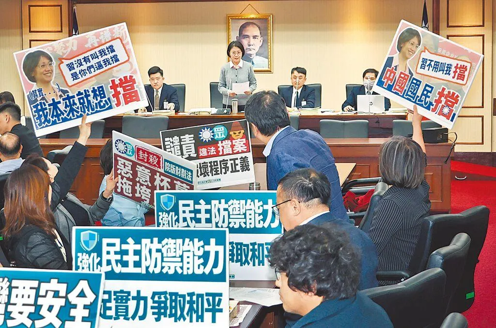 圖為在立法院去年12月的程序委員會中，民進黨立委舉標語抗議藍白及召委翁曉玲（中上）擋國防特別預算條例排入議程。（圖/資料照）
