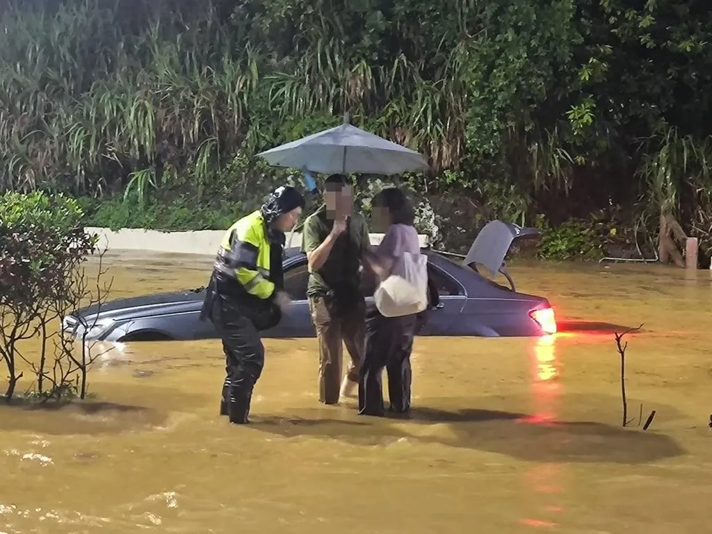 北部22日降下豪雨,台2線29K石門洞一帶發生大水圍困轎車事件,警消協助車上1名駕駛和1名女乘客托困。(圖/翻攝畫面)