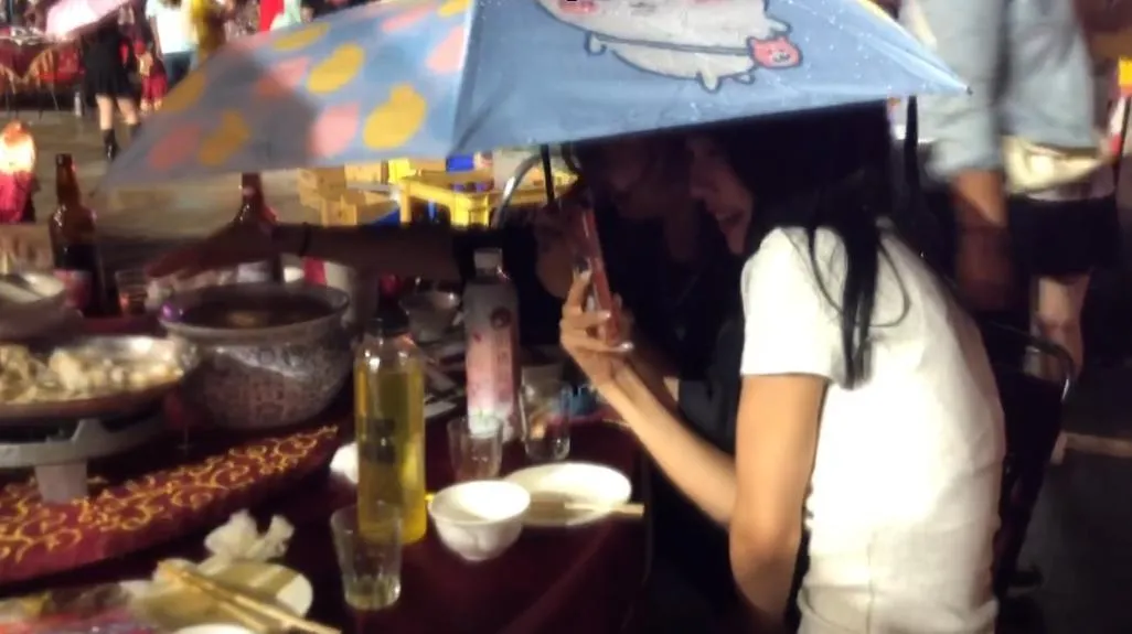 有部分熱血民眾索性直接在座位上撐起雨傘、穿上雨衣,頂著風雨繼續大口吃肉、喝湯,一邊苦笑直呼這根本是「前所未有的經驗」,大雨讓菜餚「自動加一味」,雖然變成了「落湯雞」,但氣氛依舊苦中作樂、十分熱絡。(圖/翻攝畫面)