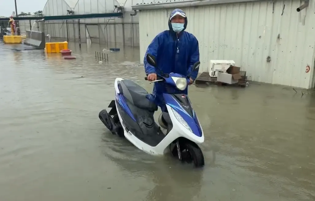 台南永康區大灣路淹水，民眾牽車步行通過。（圖／中天新聞）