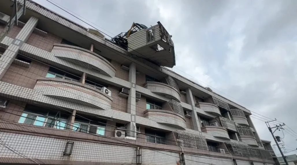 台南將軍區一民宅頂樓廢棄鴿舍遭強風吹塌，半懸空搖搖欲墜，場面驚險。（圖／翻攝畫面）