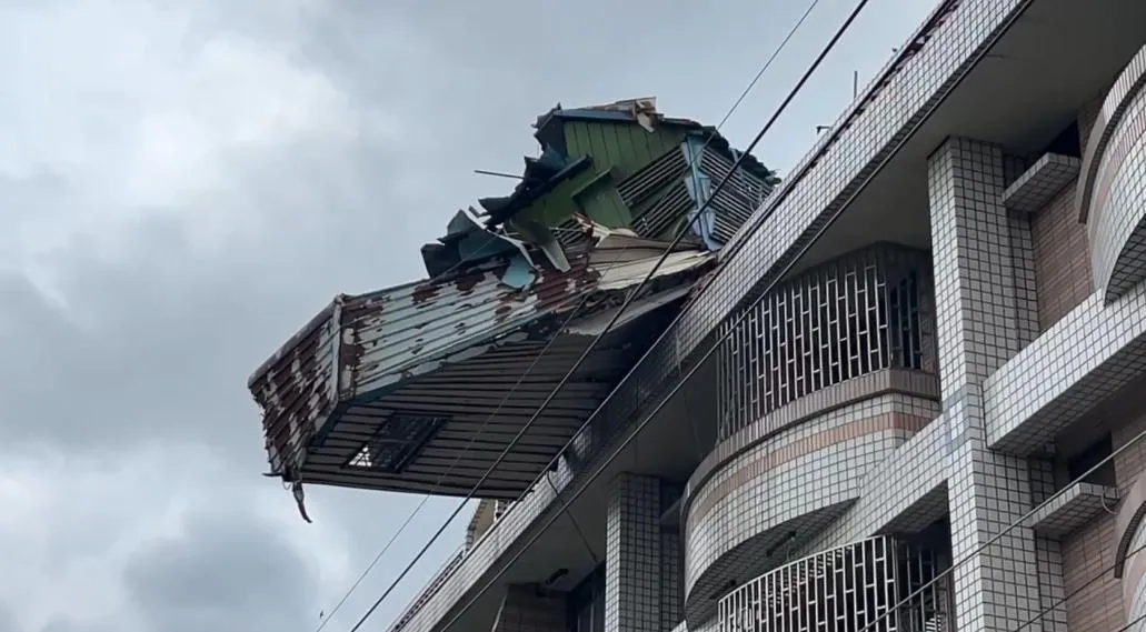 台南將軍區一民宅頂樓廢棄鴿舍遭強風吹塌，半懸空搖搖欲墜，場面驚險。（圖／翻攝畫面）