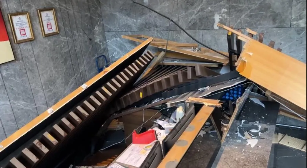 高雄市七賢一路一棟住宅大樓8日凌晨發生公安事故,大廳管理室上方天花板整片向下脫落,冷氣管線因此全數外露,管理室幾乎遭碎料掩埋。(圖/翻攝畫面)