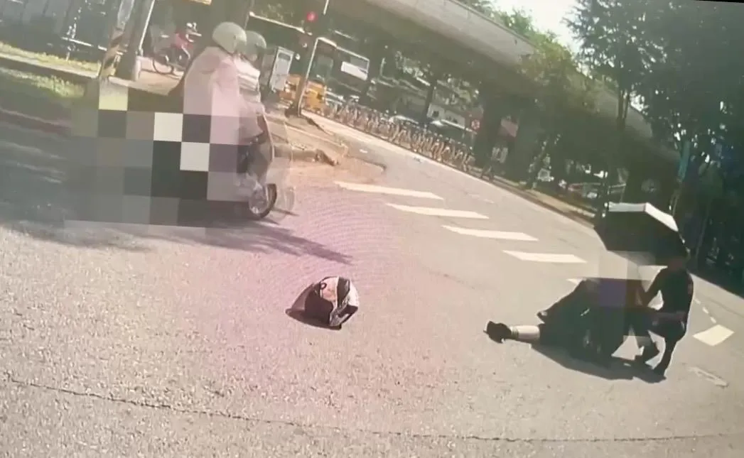 施姓員警幫摔車女騎士撐傘。（圖／翻攝畫面）