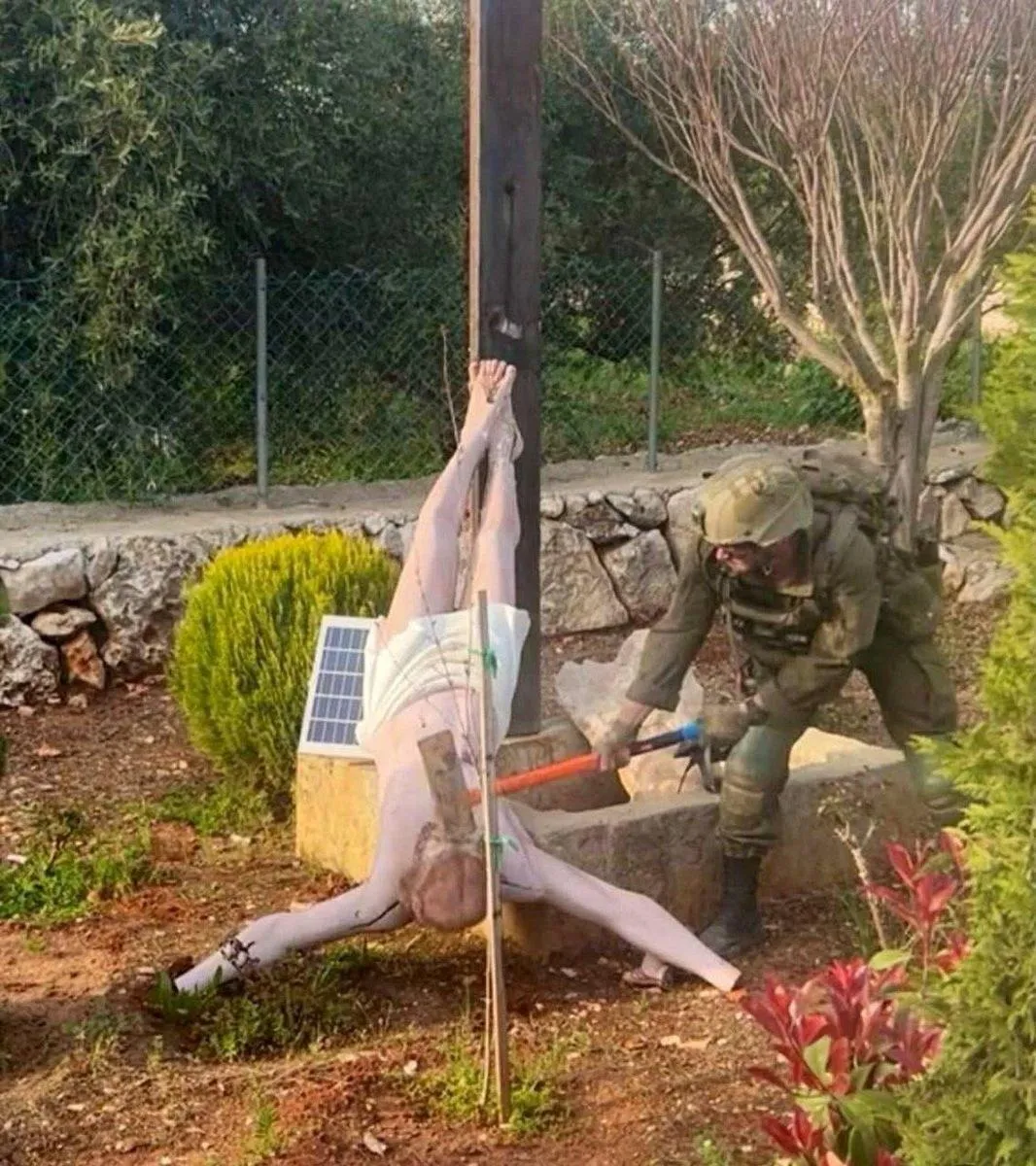以色列士兵在黎巴嫩破壞一尊耶穌受難像的頭部。（圖／路透社）
