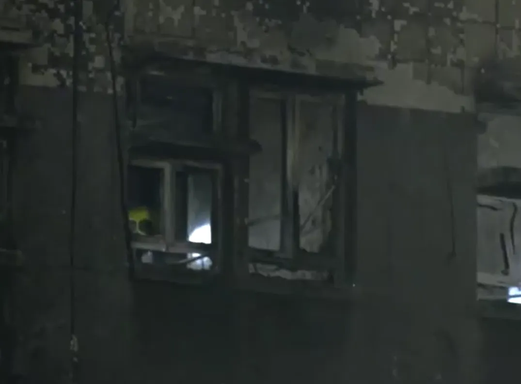 外部可見消防人員持手電筒搜索起火大樓內部。（圖／路透社）