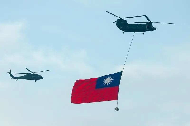 國軍空中全兵力預演，懸掛巨幅國旗的CH-47SD運輸直升機飛越總統府前上空，場面壯觀。（圖／中央社）
