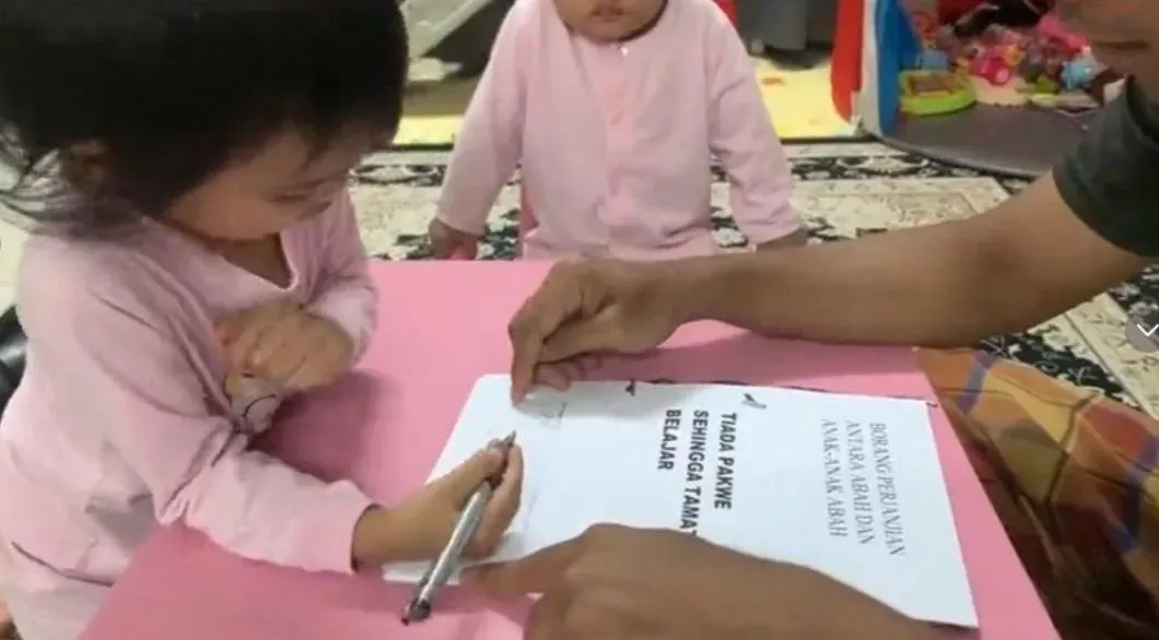 在爸爸指導下，大女兒拿筆在「協議書」上簽名。（圖／翻攝自TikTok@abah_double_sumayyah）