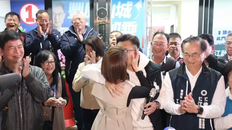 江啟臣（前排右2持麥克風者）被太太劉姿伶又親又抱，十分恩愛。（圖／江啟臣提供）