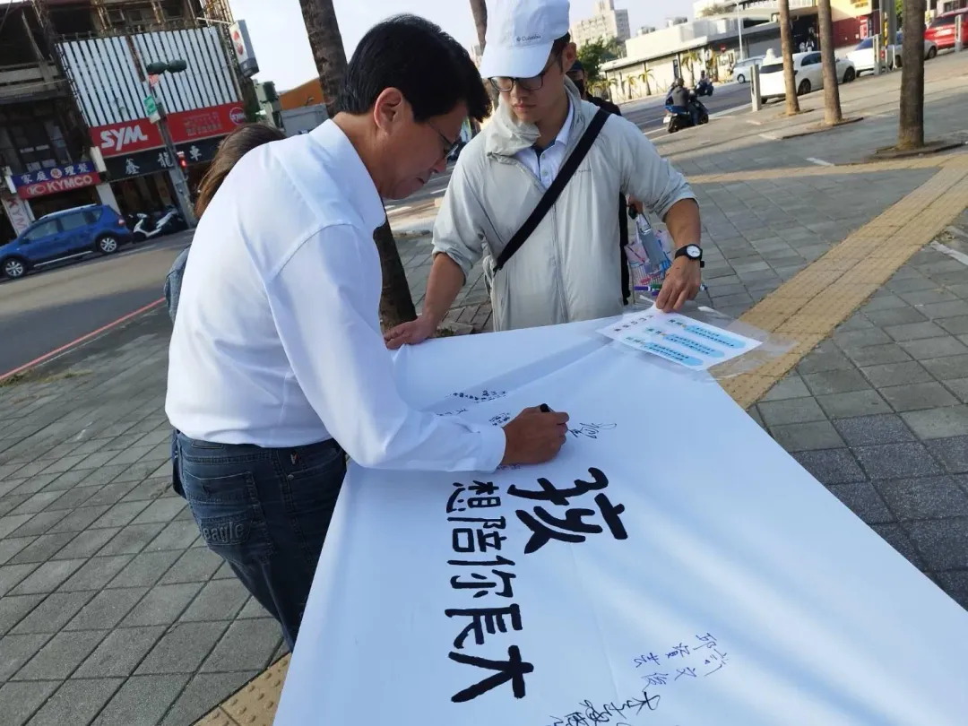 準立委謝龍介現身台南轉運站附近公園，在布條上簽名力挺「孩想陪你長大」。（圖／徐妮妮提供）