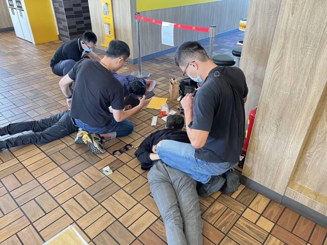 警方在速食店逮捕３名假投顧車手，將他們壓制在地。（圖／中天新聞）