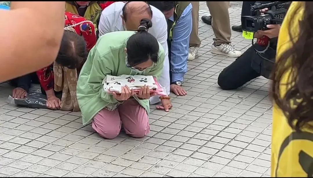 秀傳醫院護理長拿著小姊姊的衣物跪迎媽祖。（圖／中天新聞）