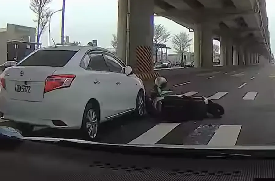 騎士倒地趴在白車前方，差點被輾了過去。（圖／翻攝畫面）