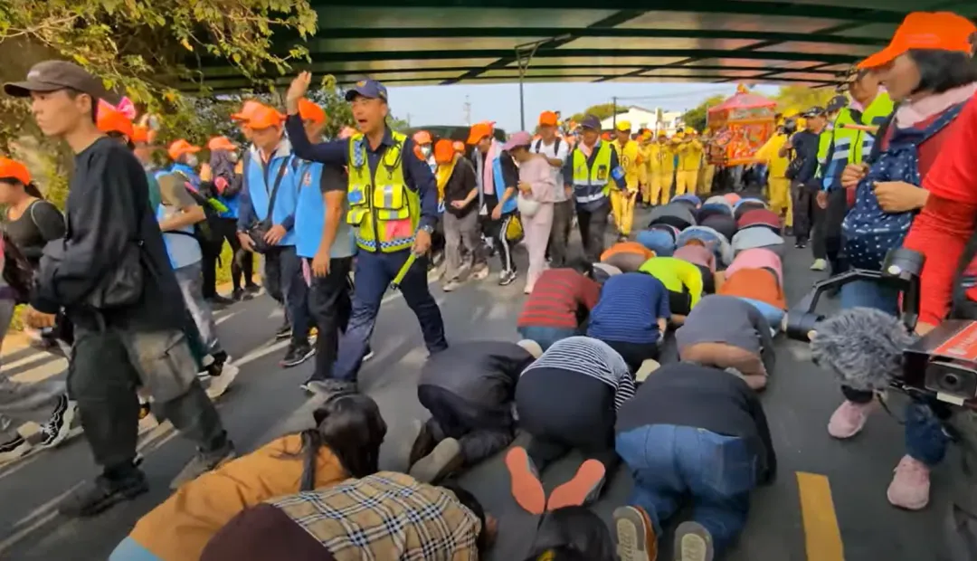 「粉紅超跑」從跪在地上的信眾上方經過賜福。(圖/翻攝白沙屯媽祖網路電視台)