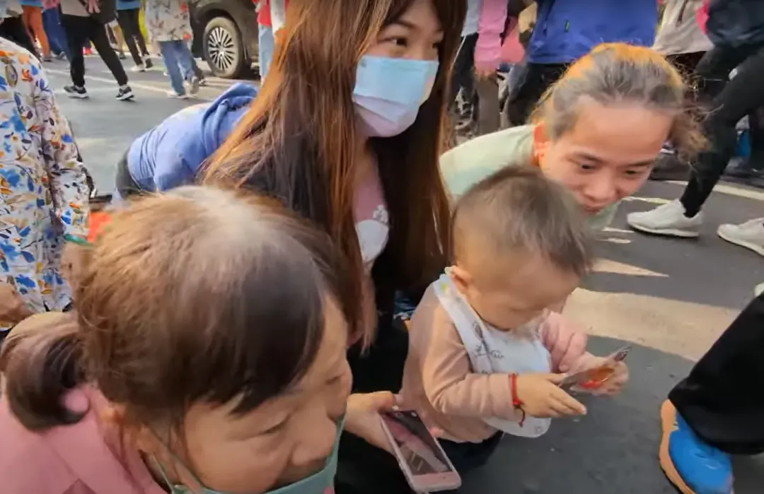 年輕夫妻抱著兒子跪在地上準備鑽轎。(圖/翻攝白沙屯媽祖網路電視台)