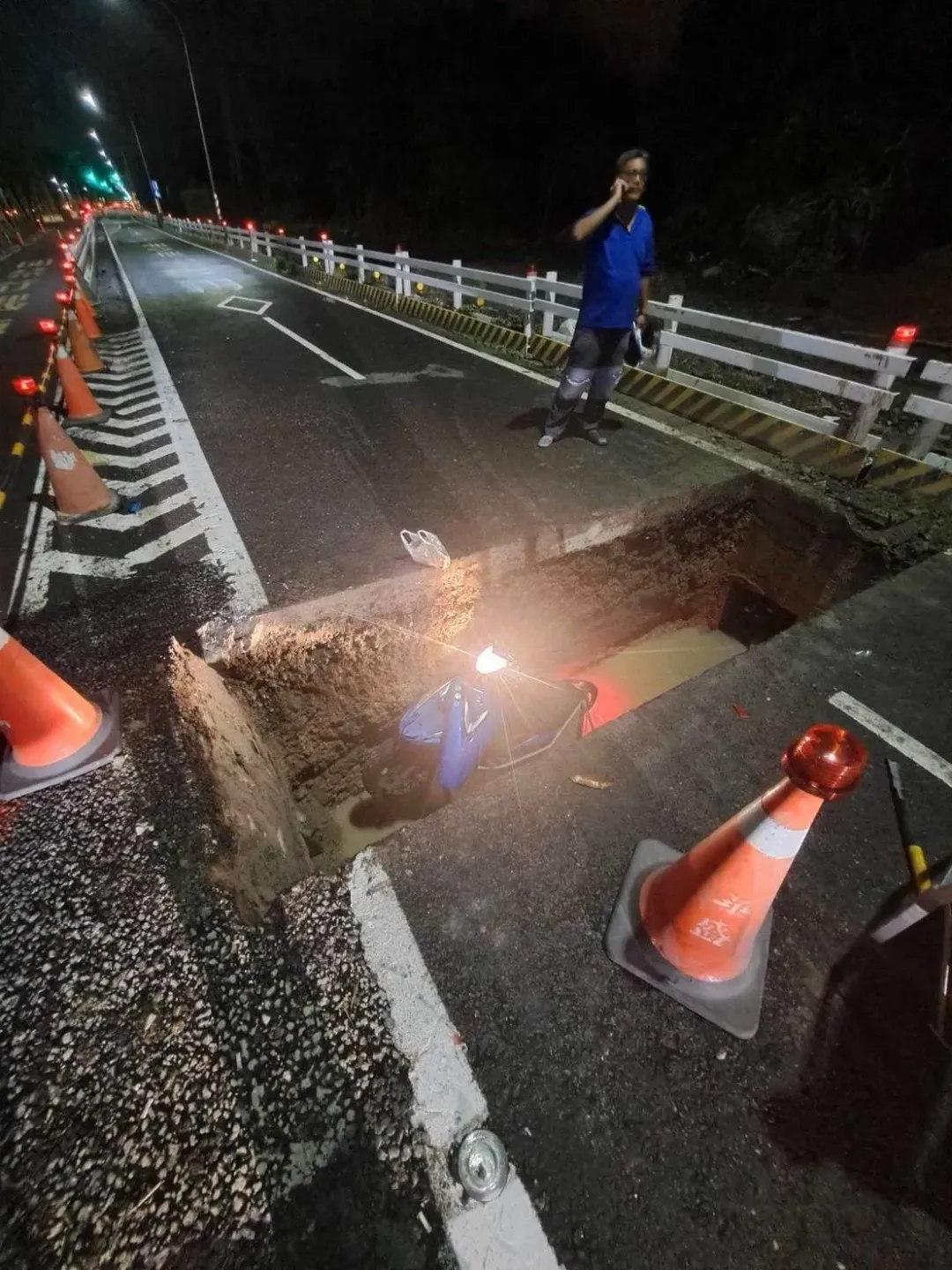 裂出的大鴻溝生吞整台機車，由於連日大雨，洞底還浸泡黃色滾滾泥水。（圖／民眾提供）