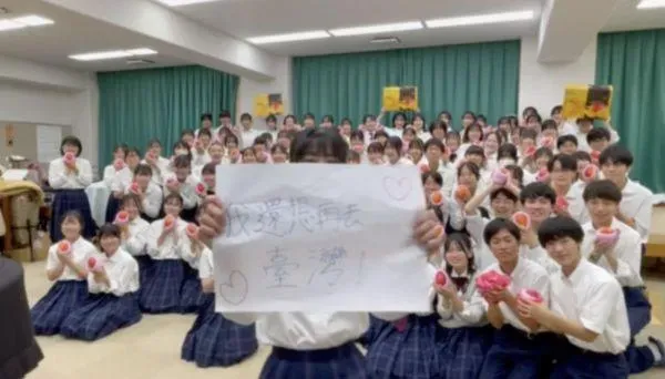 橘色惡魔拍影片感謝文化總會致贈芒果,寫大字報「我還想再去台灣!」(圖/翻攝自文化總會提供影片)