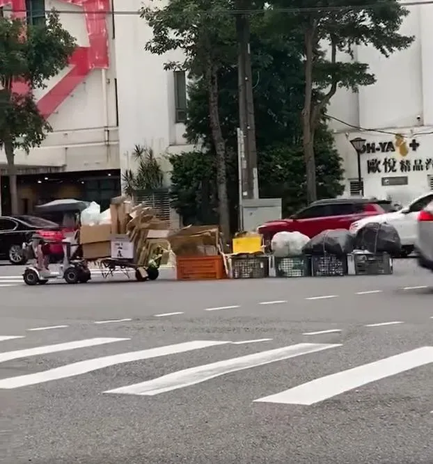 桃園拾荒阿嬤騎著電動代步車,後方載著1部推車和5個籃子,穿梭在路口車陣中,相當危險。(圖/翻攝自臉書爆廢公社)