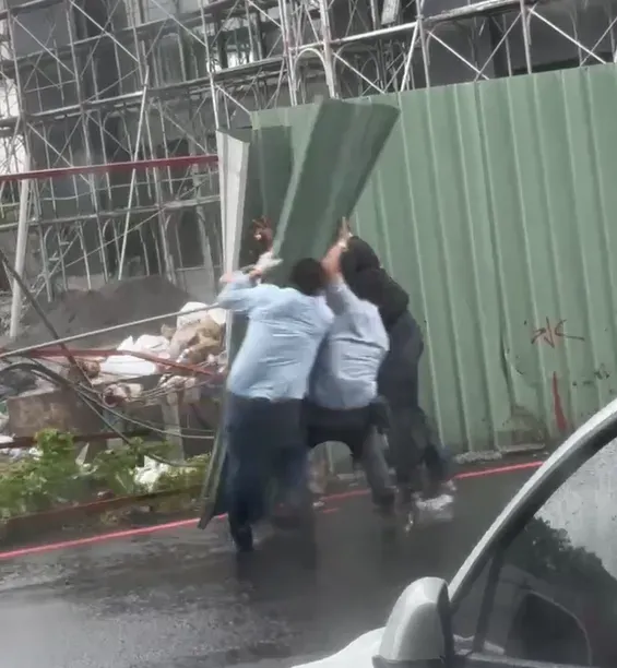 從影片畫面可見,當時4名男子同時壓著也擋不住強風吹襲,其中2人被風吹倒受傷。(圖/中天新聞)