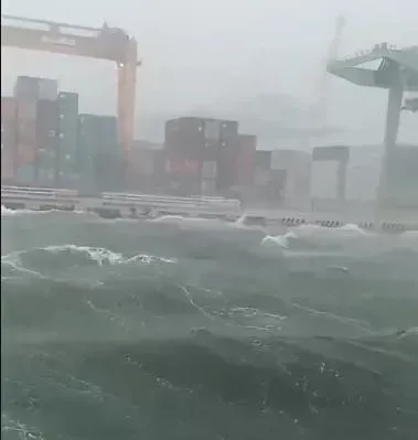 高雄港因為狂風大雨加上大潮,港區內海水洶湧,海浪淹上碼頭。(圖/翻攝畫面)
