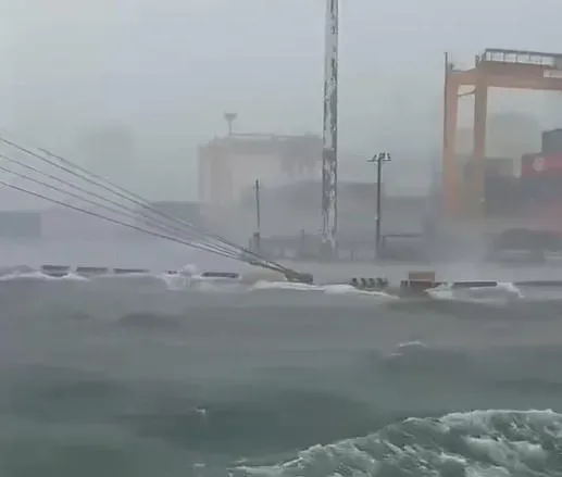 高雄港因為狂風大雨加上大潮,港區內海水洶湧,海浪淹上碼頭。(圖/翻攝畫面)