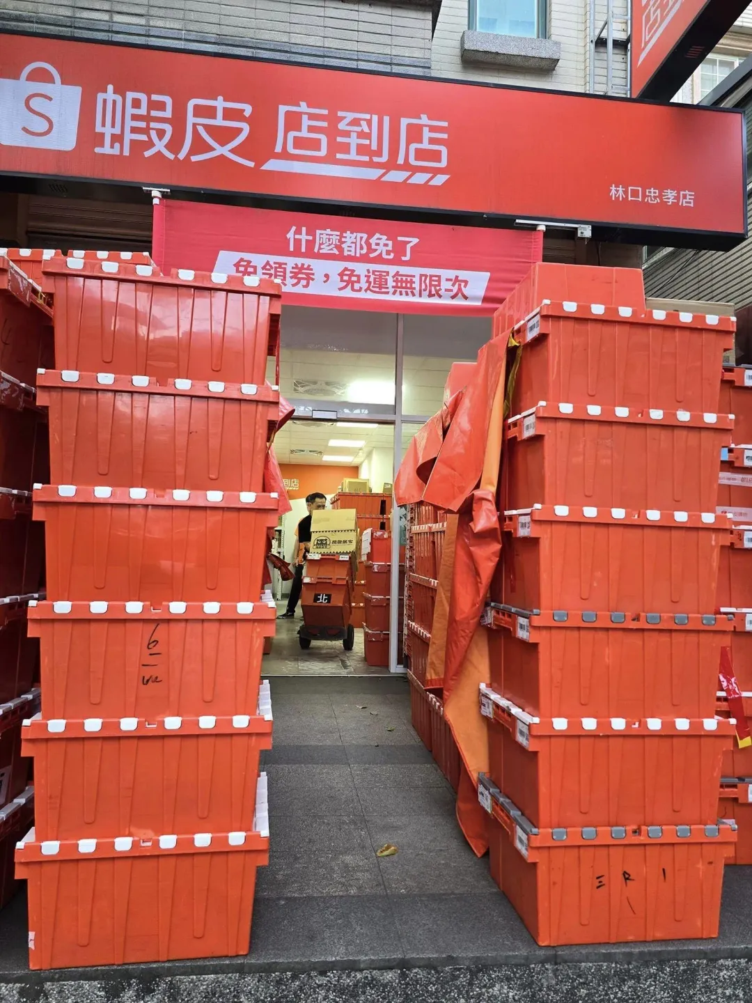 林口忠孝路的蝦皮忠孝店門外,疊滿一箱箱的橘色貨箱。(圖/翻攝自臉書「林口大家庭LinKou-Family」)