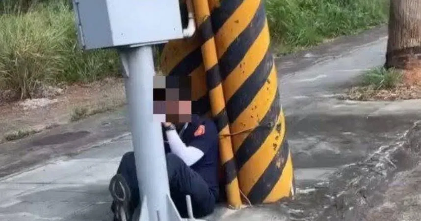 員警手持雷射測速槍蹲坐在電桿旁拍照,引發民眾質疑偷拍超速。(圖/翻攝記者爆料網)