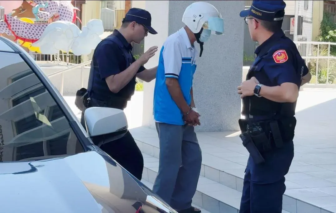 行兇的彭男頭戴安全帽戴口罩、腳穿拖鞋、雙手上拷，在警方押解下進入派出所。（圖／網友提供）