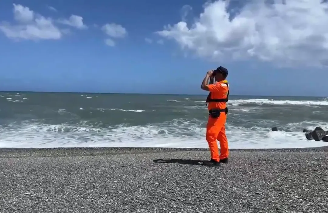 海巡人員也在岸際持望遠鏡搜索有無墜機線索。（圖／翻攝畫面）