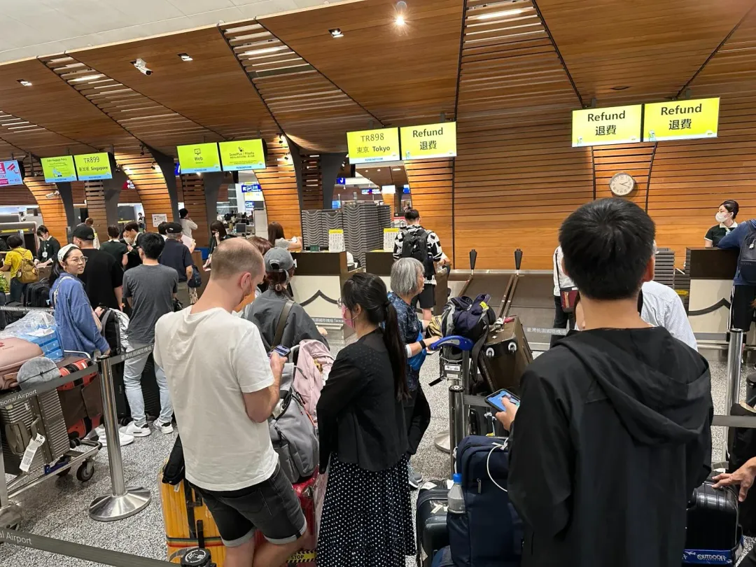 酷航21日發生機械故障與天氣原因導致取消班機,大批乘客在櫃檯前排隊等著退費。(圖/中天新聞)