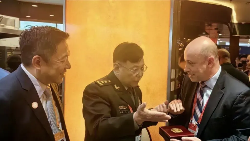 何雷贈送人民解放軍軍事科學院的徽章。(圖/北京日報)