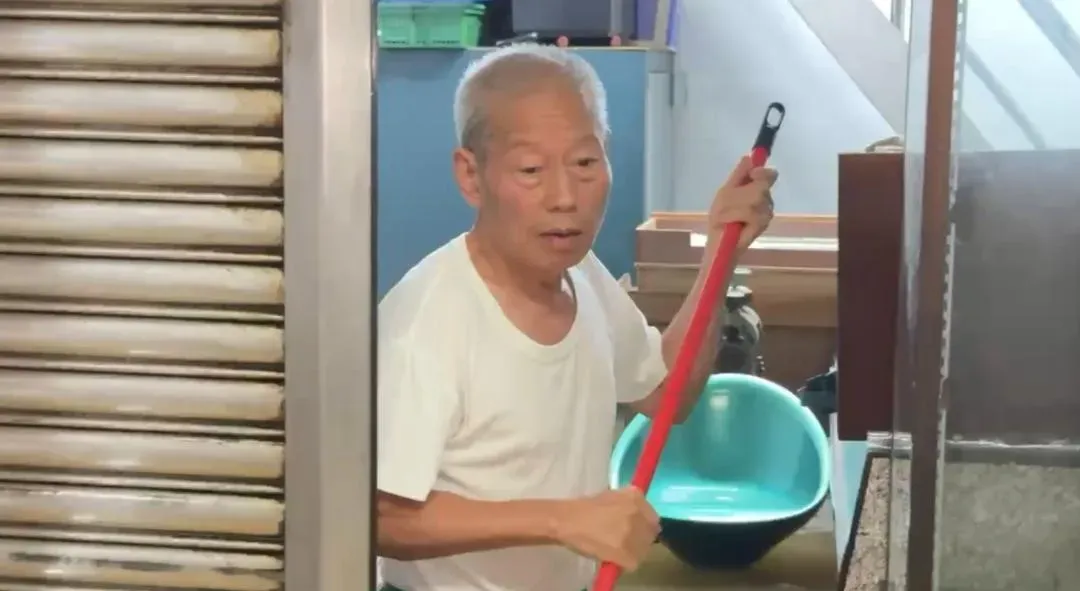 阿伯拿著掃把將積水推出家門外，仍試圖與洪水搏鬥。（圖／翻攝畫面）