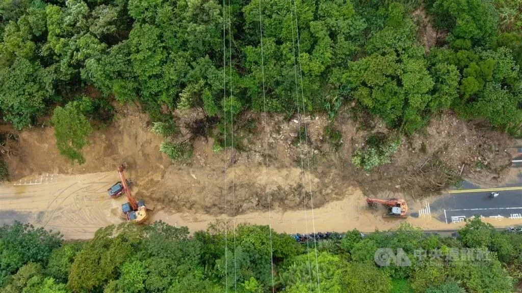 基隆4日凌晨大雨，新豐街海中天社區前山坡大面積土石崩落走山，長度約100公尺，交通中斷，請用路人提前改道，基隆市工務處已派怪手等大型機具搶通。（圖/中央社/記者王騰毅攝）