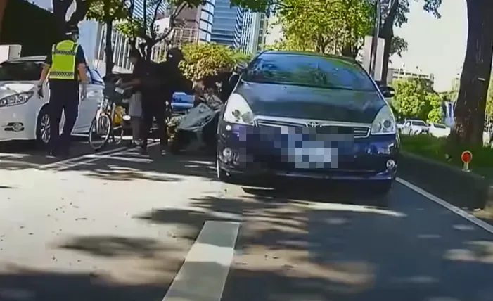 男騎士比完「倒讚」才過了3秒鐘，就因為單手握車把重心不穩，與左側轎車發生擦撞，當場痛摔倒地。（圖/翻攝畫面）