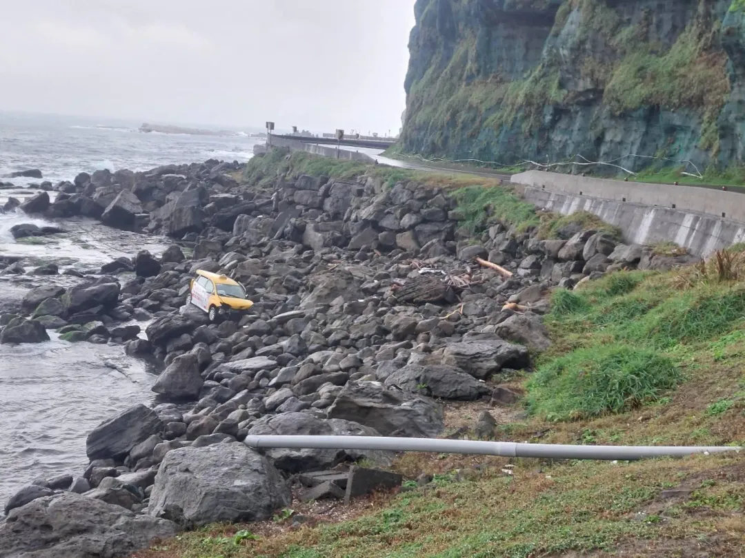 瑞芳區台二線上,計程車不明原因衝破護欄,車輛卡在岸邊石堆上,駕駛救出送醫命危。(圖/翻攝畫面)