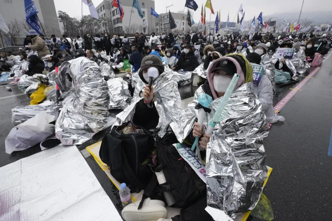 抗議者披鋁箔毯在總統官邸附近參加集會，要求逮捕尹錫悅。（圖／美聯社）