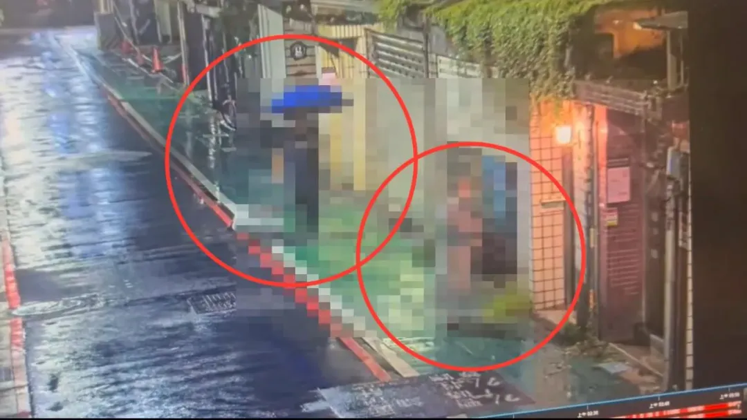 2名信眾撐著雨傘運屍前後走進精舍。(圖/翻攝畫面)